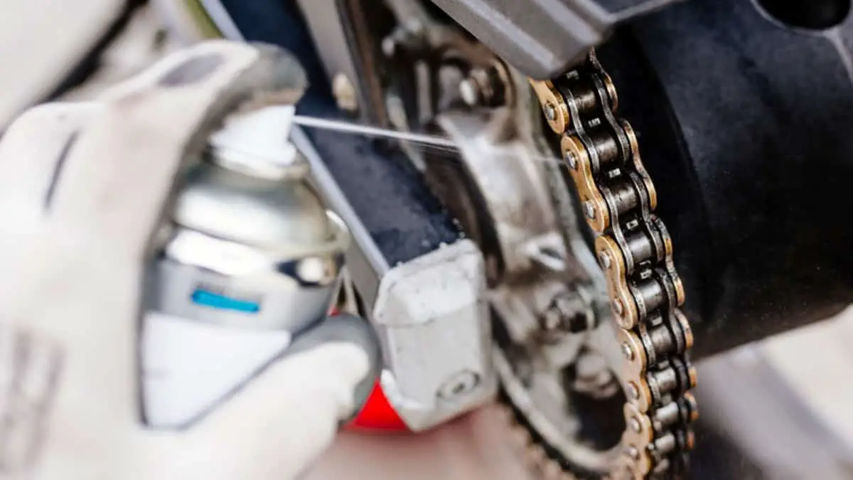 spraying degreaser on motorcycle chains