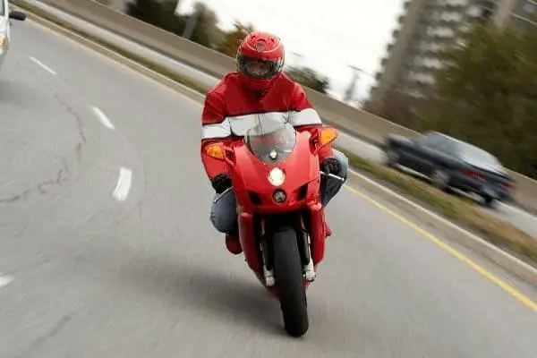 man riding red motorcycle on highway