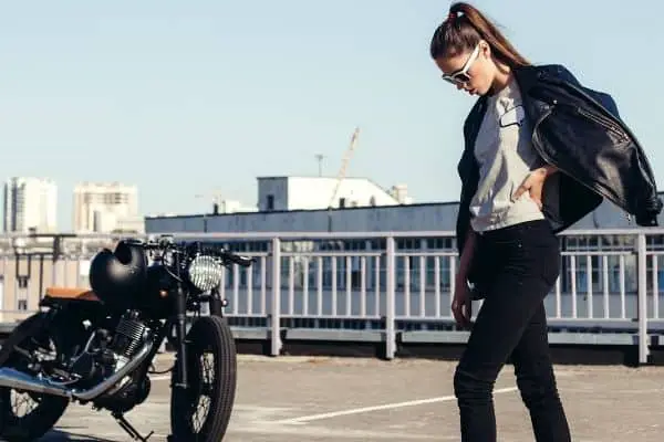 Stylish woman near motorcycle wearing casual clothes and leather jacket