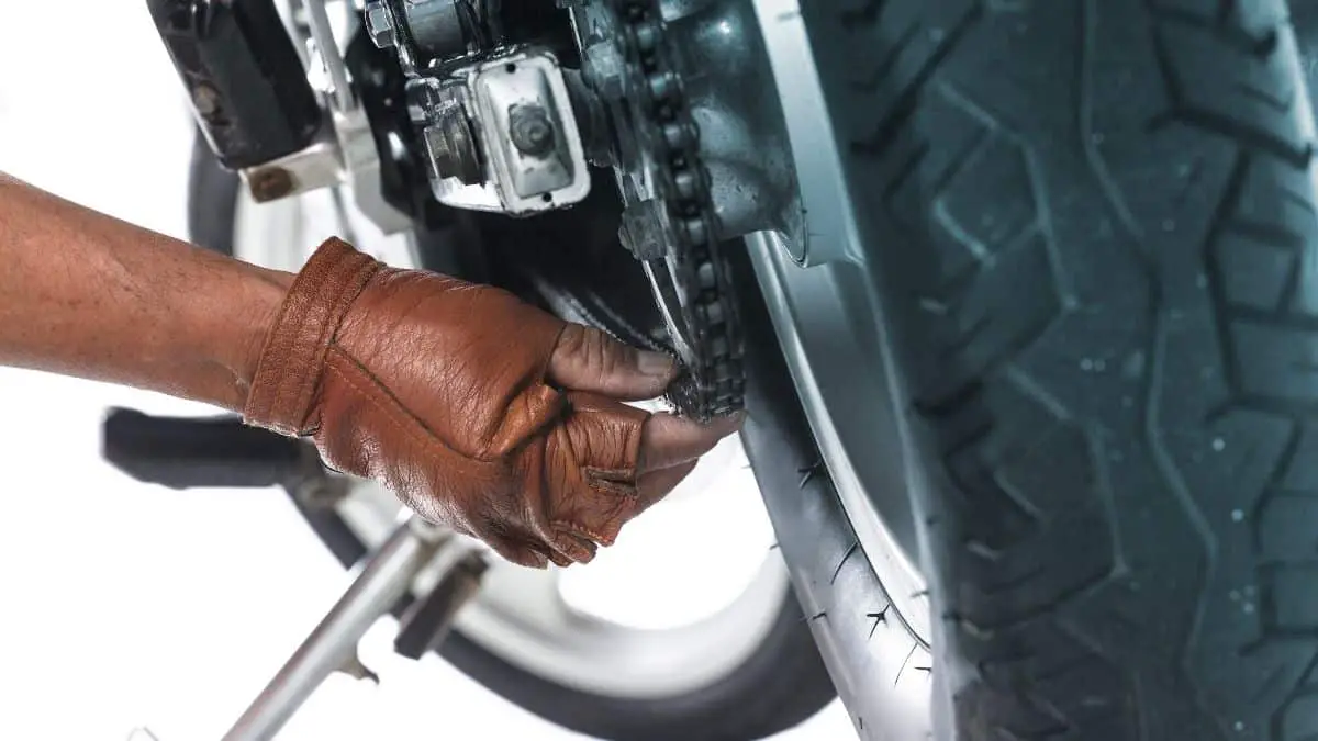 A Leather Gloved Hand Adjusting A Motorcycle Chain