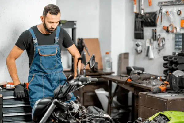Biker Repairman Trying To Figure Out How To Move Motorcycle In Garage Easily