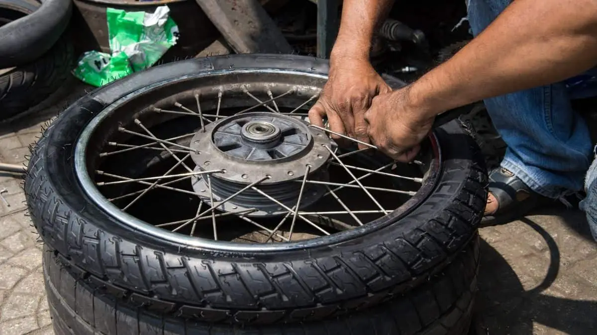 A Man Removing Motorcycle Tire From Wheel