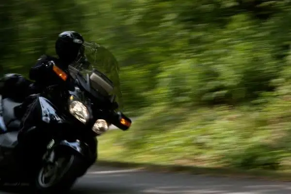 A Motorcyclist In Black Riding Fast