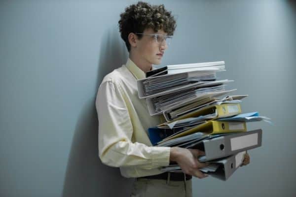 Young Man With Glasses Carrying Heavy Folders