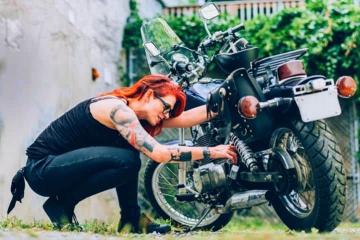 A Woman Examines Her Motorcycle