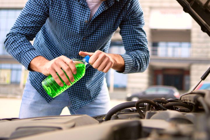 Man Is Holding Coolant In Front Of Car
