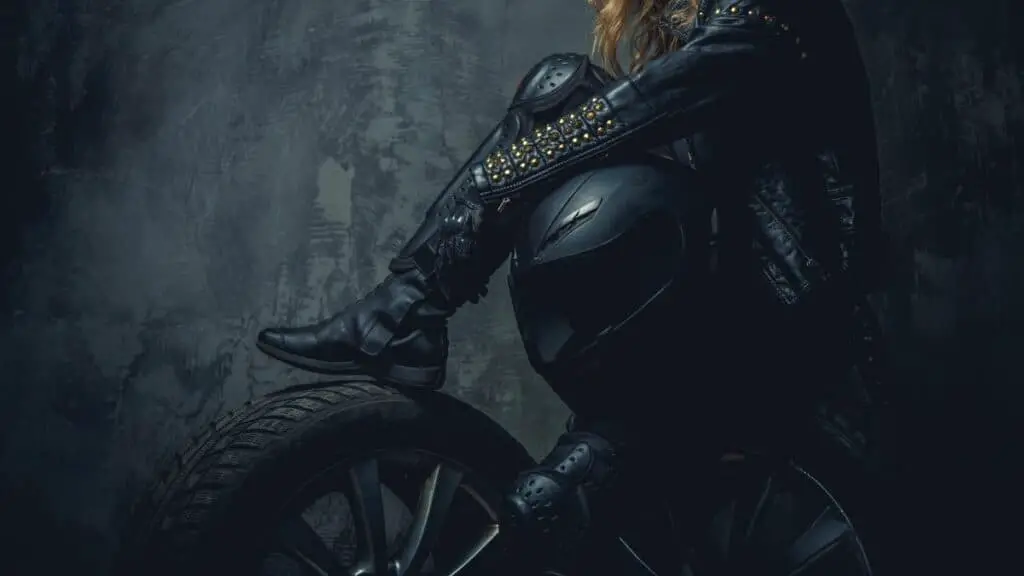 Female Motorcycle Rider In Full Gear Sitting On A Tire