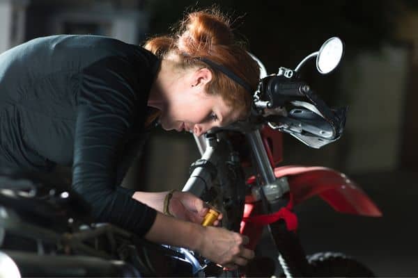 A Woman Inspecting A Motorcycle