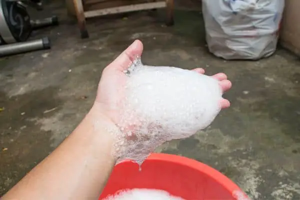 Handful Of Suds Over A Red Plastic Washbowl