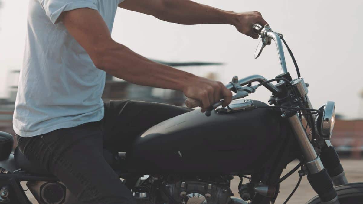 Man Sitting On A Motorcycle With His Hand On The Right Handlebar