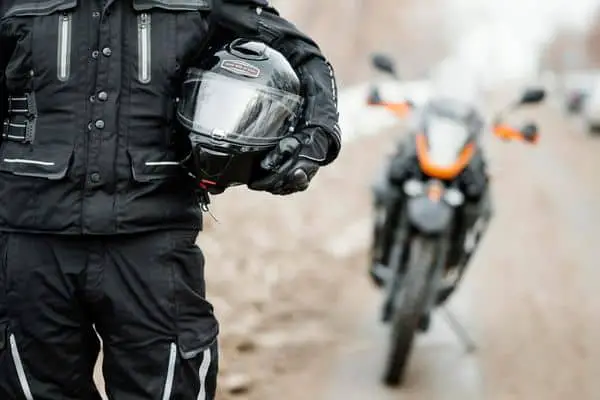 Rider Standing Near Their Motorcycle And Holding A Helmet