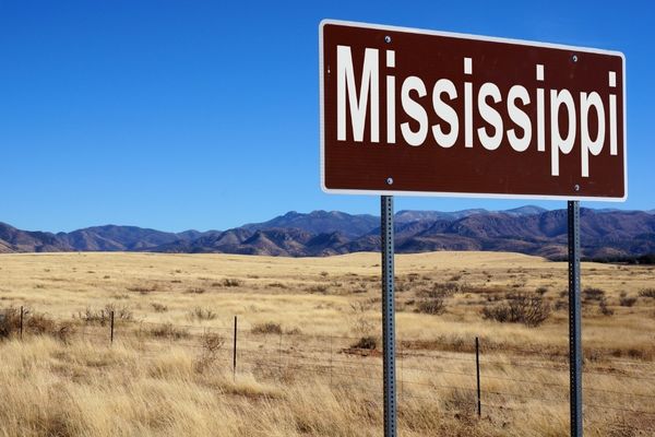 Mississippi Road Sign Against A Background Of Savannahs And Faraway Mountains