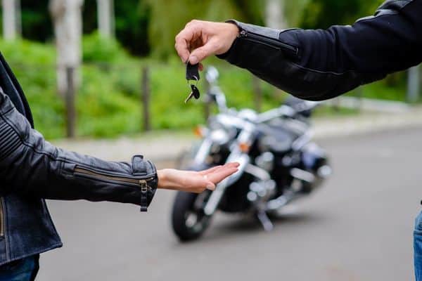 Two People Exchanging Keys For A Motorcycle