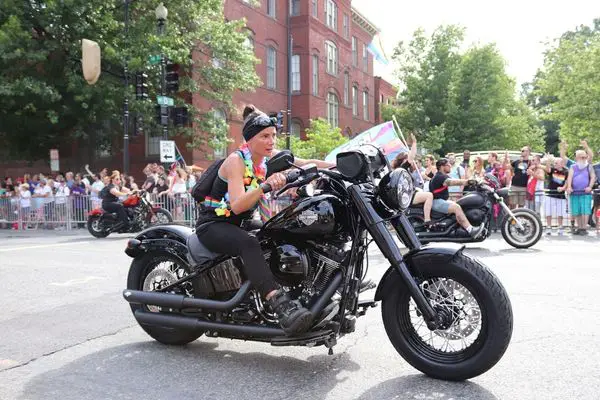 A Woman Riding A Big Black Motorcycle On A Gay Pride Parade